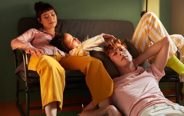 Dwie studentki odpoczywają na sofie, a student relaksuje się na podłodze w pokoju w akademiku.