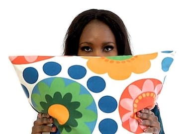 Dyna from Ellas lo Bordan holding a cushion from the ÅTERSTÄLLA collection