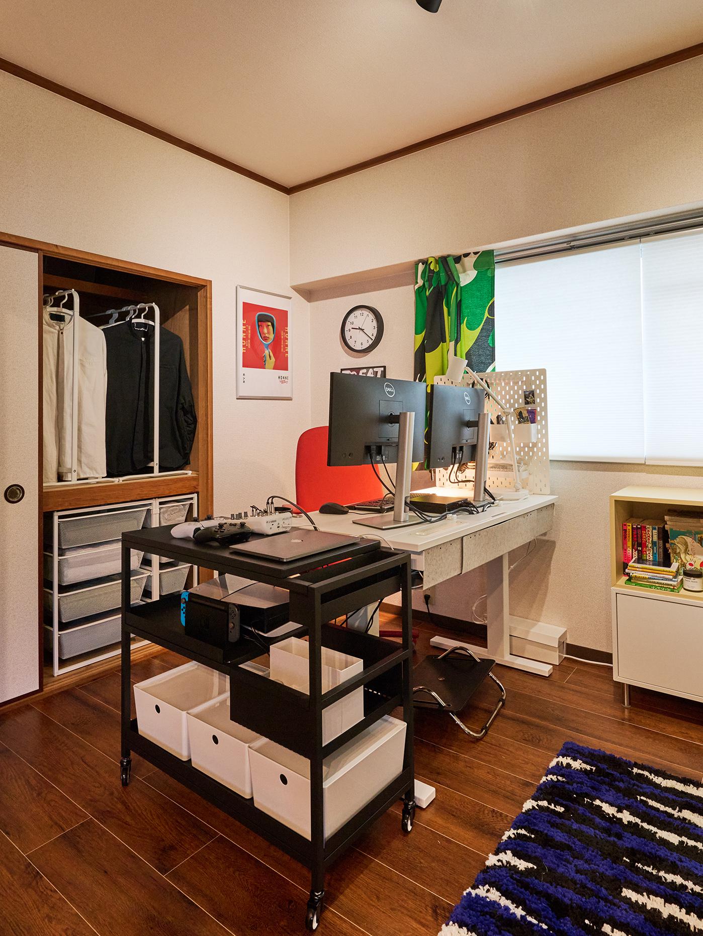 デュアルモニターと赤い椅子、ワゴン、カラフルなカーテンがある整理されたホームオフィス。