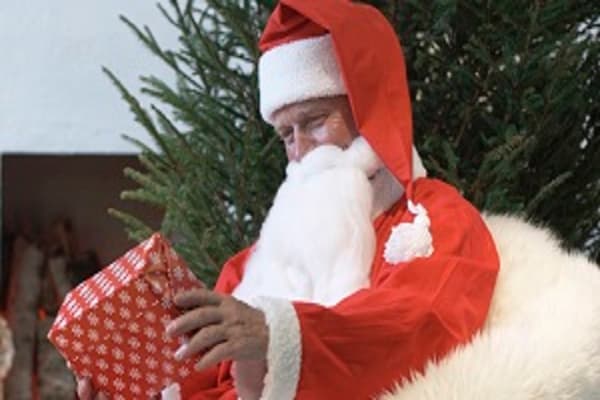 Santa Claus sitting in a fuzzy chair holding a present.