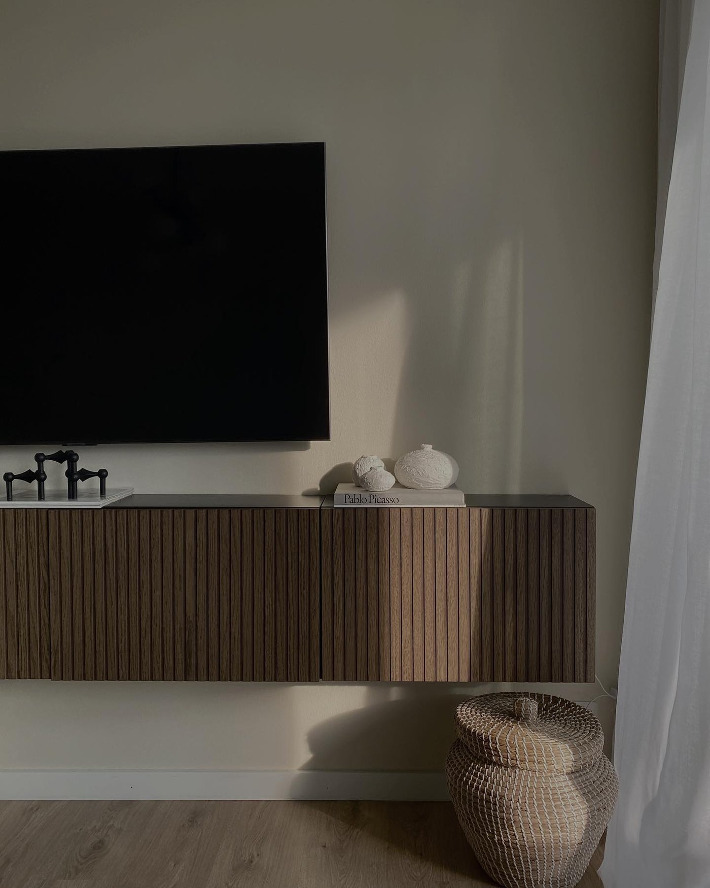 Een aan de wand gemonteerd BESTÅ tv-meubel met donkerbruin walnoot deurtjes in de woonkamer.