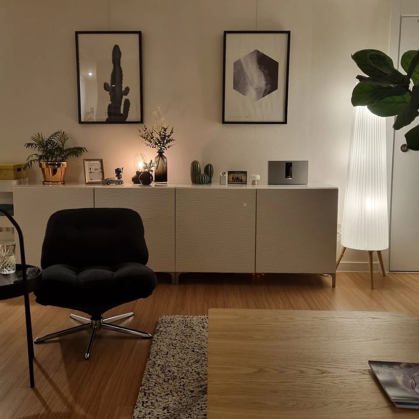 Een BESTÅ opbergmeubel met beige deurtjes en vele woonaccessoires in de woonkamer.