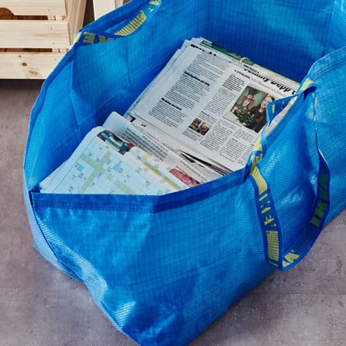 Een blauwe IKEA tas, voor de helft gevuld met kranten.