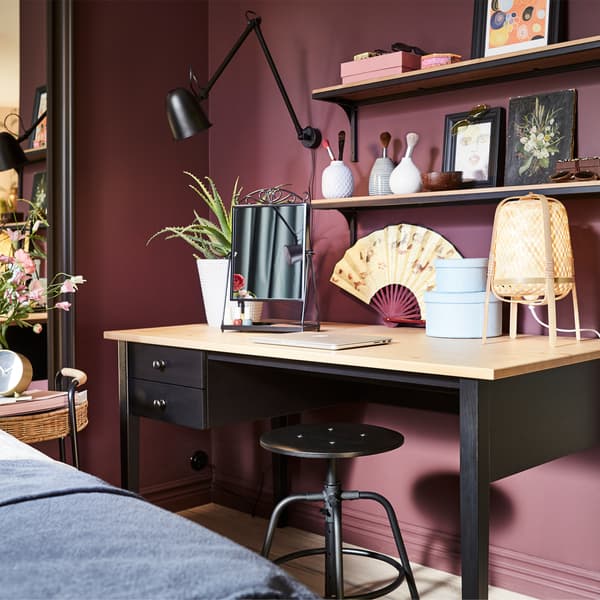 Een bureau in zwart, massief grenen, een zwarte wandlamp, een tafellamp in bamboe en een zwarte kruk.