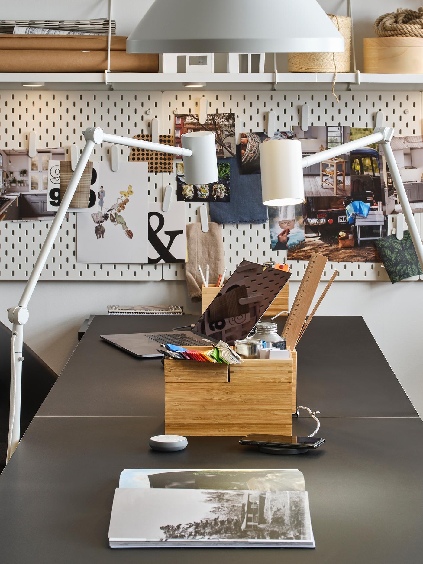 Een bureau met daarop een houten opbergdoos en daarachter een achterwand met foto's.