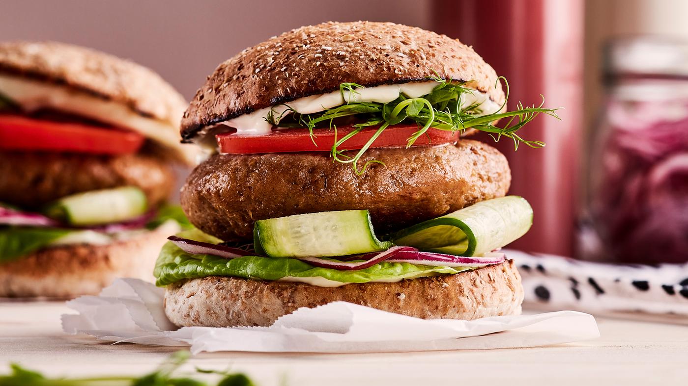 Een burger gemaakt van VÄRLDSKLOK plantaardig gehakt met komkommer, rode ui, sla, tomaat, spruitjes en mayonaise.