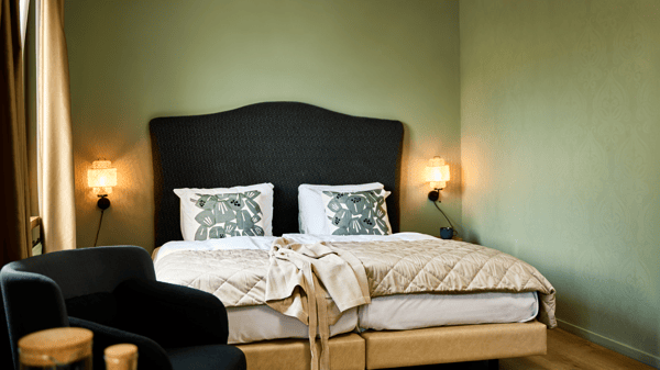Een chique bed in een hotelkamer met frisgroene muren