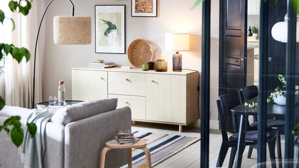Een ERSNÄS buffetkast in een berkenhouteffect tegen een witte muur. Ervoor staan een beige/bruine SÖDERHAMN zetel en een vloerlamp.