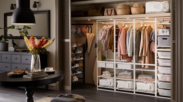 Een grote hal met een ingebouwde kledingkast met daarin een JONAXEL opbergcombinatie, kleding, opbergdozen en manden.