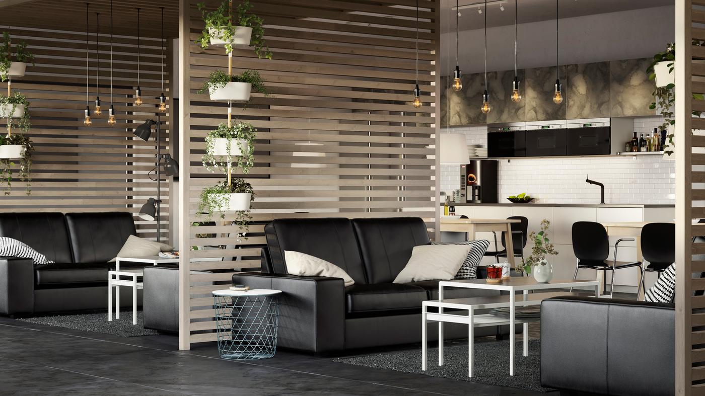 Een grote, luchtige kantoorruimte met KIVIK banken in zwart leer en scheidingswanden van lattenhout.