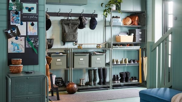 Een hal met OMAR stellingkasten met daarop schoenen, laarzen en metalen REJSA bakken en twee PINNIG rekjes met drie haken aan de wand.