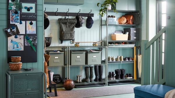 Een hal met OMAR stellingkasten met daarop schoenen, laarzen en metalen REJSA bakken en twee PINNIG rekjes met drie haken aan de wand.