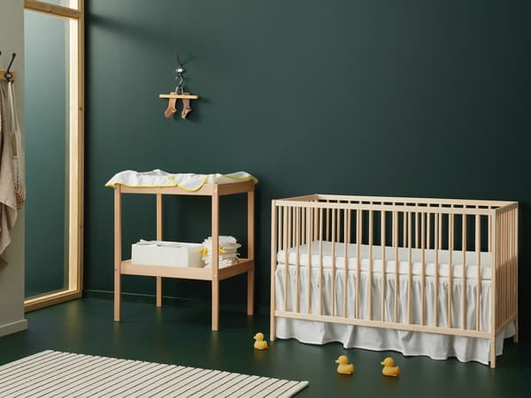 Een houten babybed en houten commode van de SNIGLAR serie