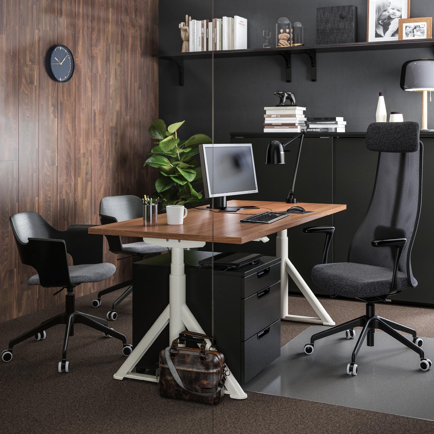 Een houten bureau met witte poten en een zwarte bureaustoel