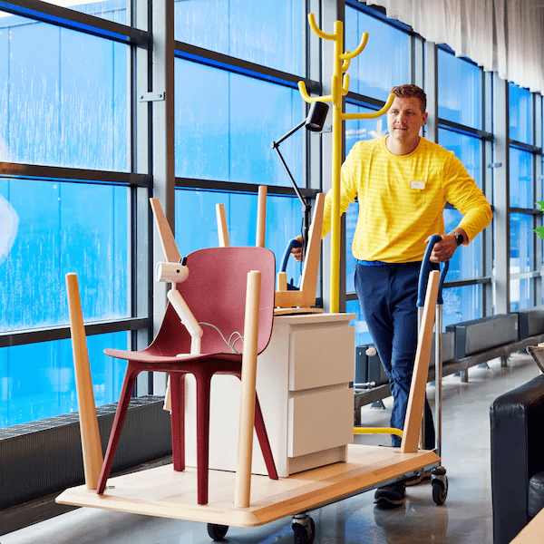 Een IKEA medewerker die meubels op een kar heeft staan die naar de tweedekanshoek gaan