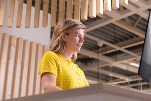 Een IKEA medewerker met een geel IKEA T-shirt aan kijkt op een computerscherm.