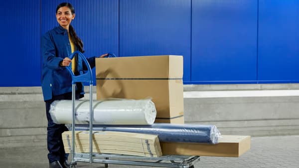 Een IKEA medewerkert duwt een trolley met pakketten