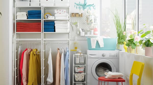 Een JONAXEL opbergsysteem met hangende kleding en ruimte voor een wasmachine.