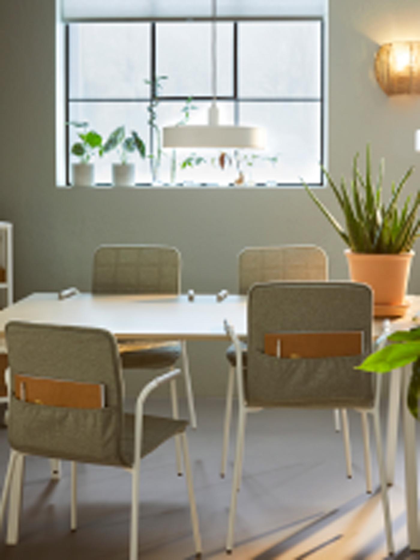 Een kantoorruimte met ramen in industriële stijl en LÄKTARE vergaderstoelen in lichtgroen en wit die rond een tafel staan.