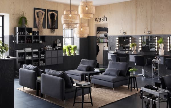 Een kapsalon ingericht met lage, donkergrijze SÖDERHAMN fauteuils en wandkasten waarin shampoo uitgestald staat.
