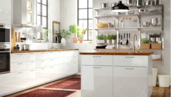Een keuken met een hoogglans wit/houten eiland, een roestvrijstalen wandrek met planken en krukken in grenen/zwart.