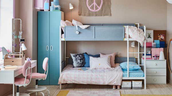 Een kinderkamer voor twee met een wit VITVAL stapelbed, een MICKE bureau en twee roze VIMUND bureaustoelen voor kinderen.