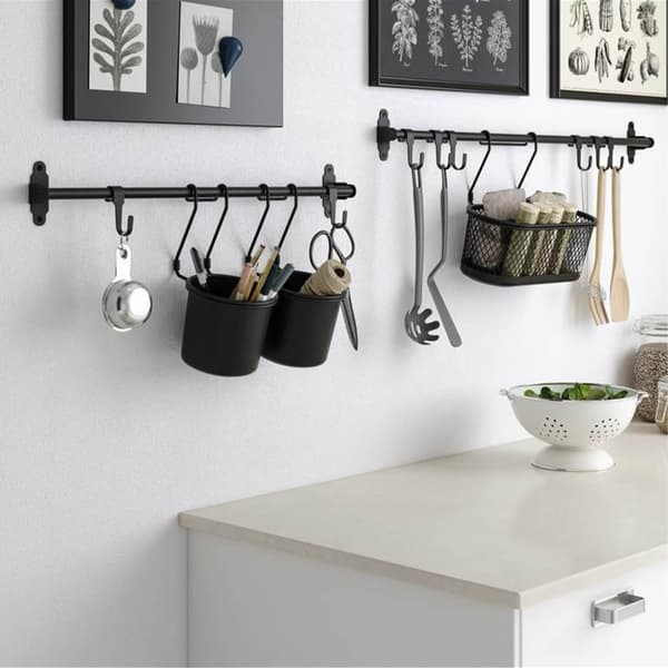Een lichte, minimalistische keukenhoek met een witte kast, wanddecoratie en een ophangsysteem met mokken, keukengerei en mandjes.