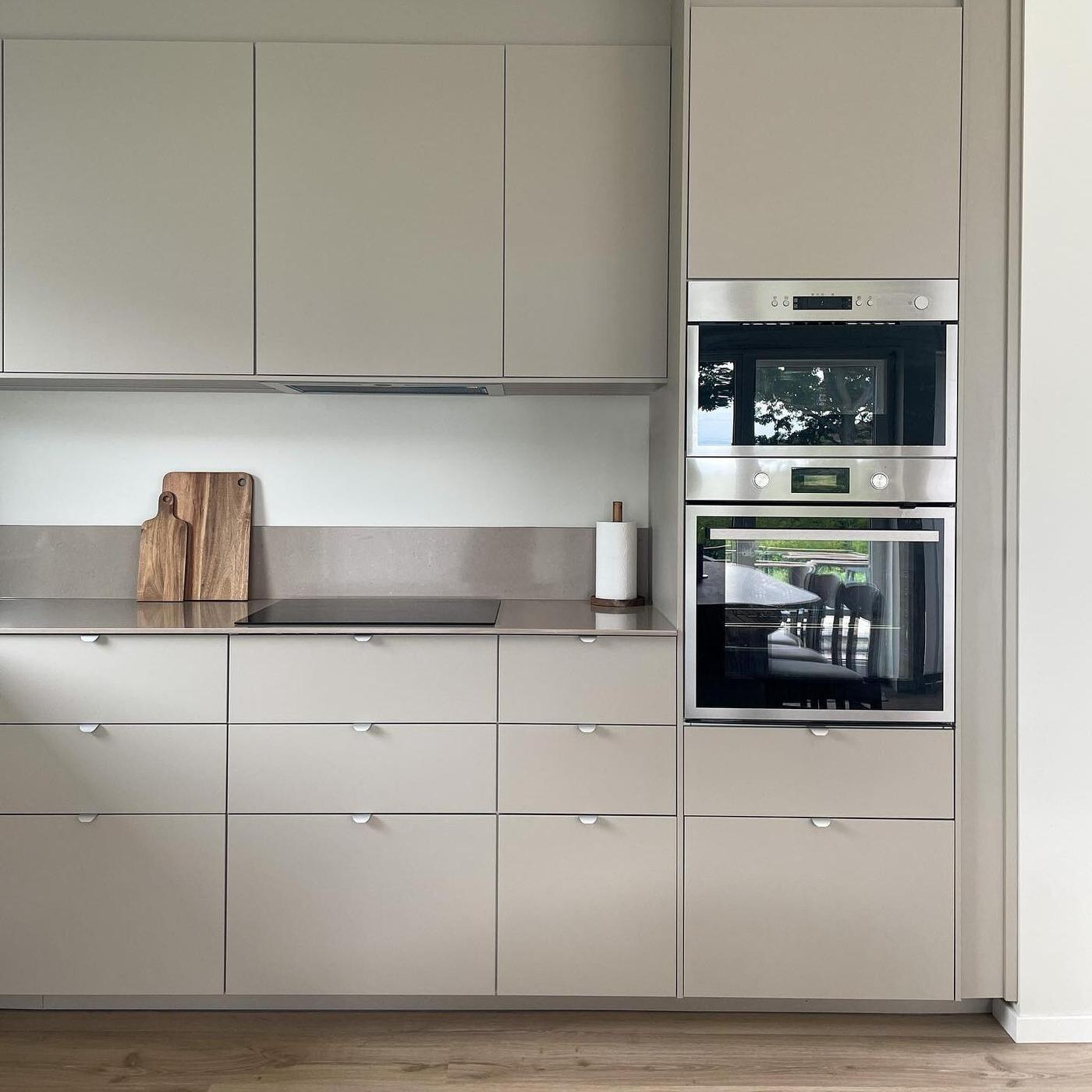 Een lichtgrijze keuken met bovenkastjes en twee ovens