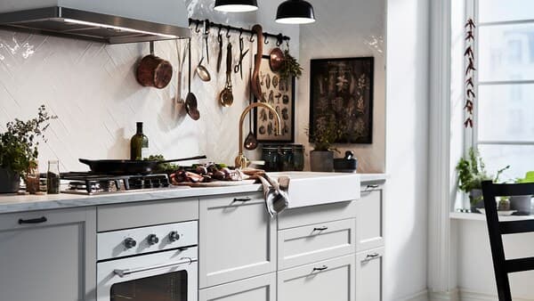 Een lichtgrijze LERHYTTAN keuken met een wit werkblad met marmerpatroon en een witte spoelbak met zichtbaar front.