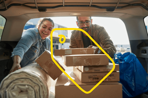 Een man en een vrouw gooien hun auto vol met hun nieuwste IKEA-aankopen.