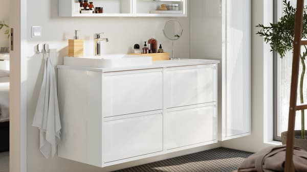 Een moderne badkamermeubel met een witte wastafel, lades en toiletartikelen op het aanrecht