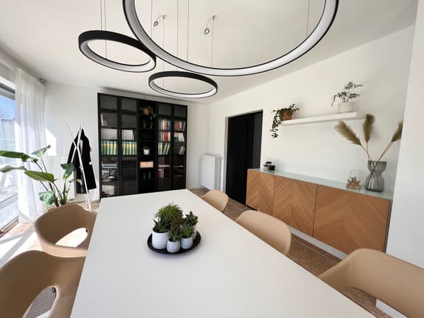 Een moderne eetkamer met een witte tafel en beige stoelen