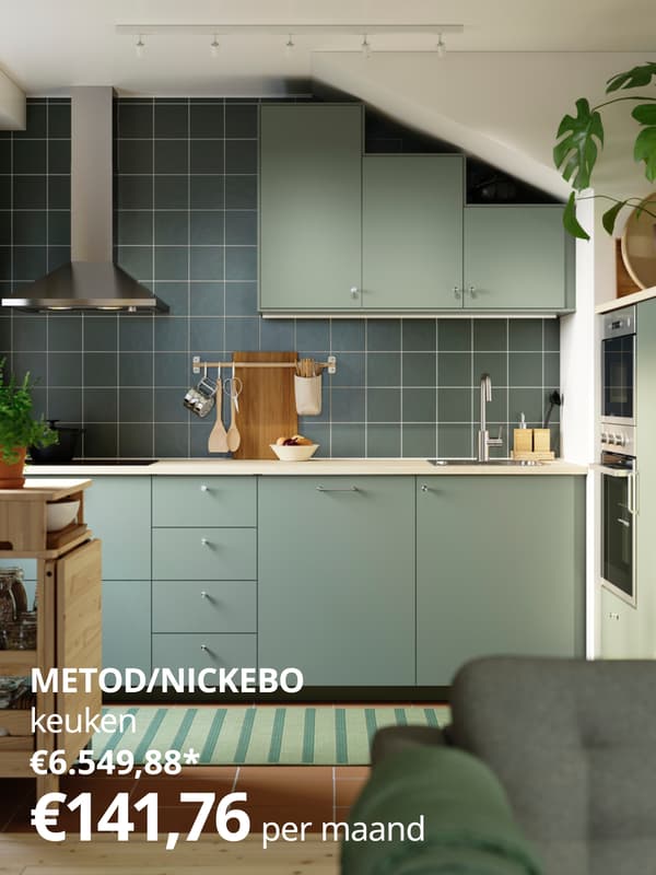 Een moderne keuken met lichtgroene kasten, een donkergroene tegelwand, een roestvrijstalen dampkap, terracottavloer en een mix van keukengerei, planten en accessoires die de ruimte karakter geven.