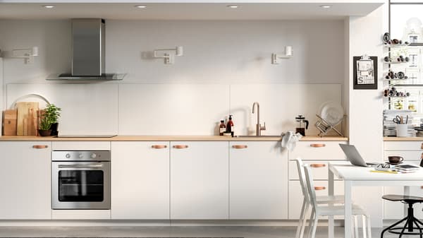 Een moderne keuken met witte kasten, een roestvrijstalen oven en een kleine eethoek