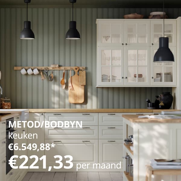 Een moderne keuken met witte kasten, houten werkbladen, een kookeiland met barkrukken, zwarte hanglampen en een houten rek met keukengerei boven het aanrecht.