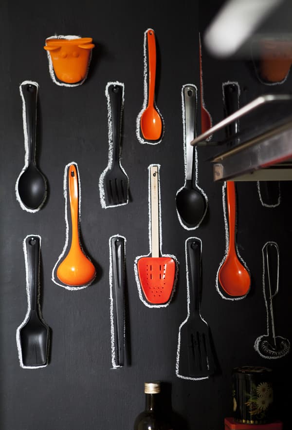 Een muur met bordverf als eetgerei‑opberger en kleurrijk display in de keuken.