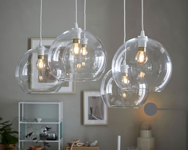 Een opstelling van vijf ronde IKEA JAKOBSBYN hanglampenkappen van helder glas waar je de lichtbron door kan zien.
