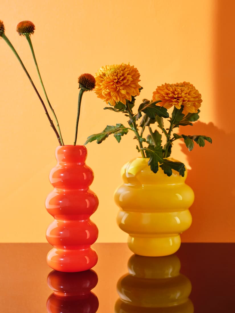 Een oranje en gele vaas met bloemen