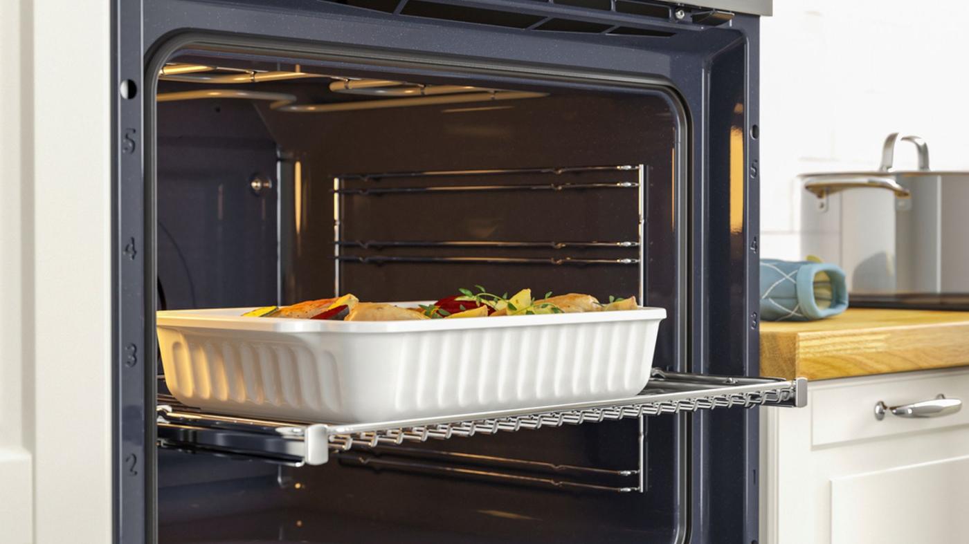 Een oven staat open met een ovenschaal gevuld met voedsel. 