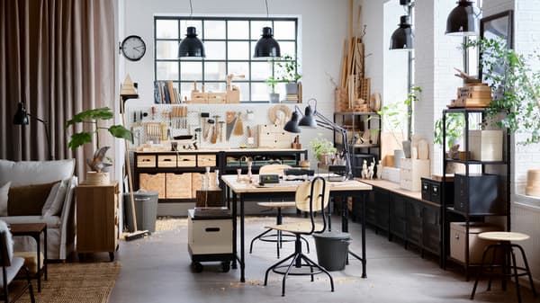 Een studio in industriële stijl met hoge plafonds, meubels van hout en zwart metaal, en grote ramen.