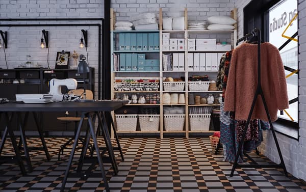 Een tafel met daarop een naaimachine en op de achtergrond allemaal naaispullen