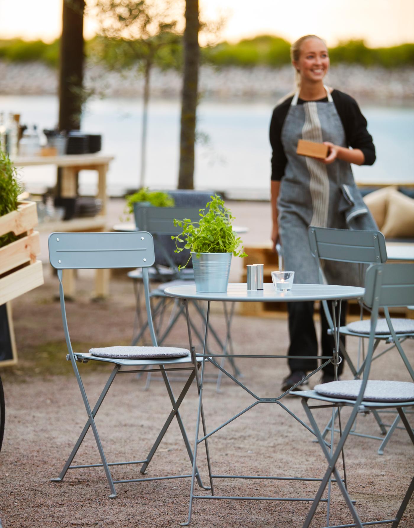 Een terras met lichtblauwe tafel en stoelen.
