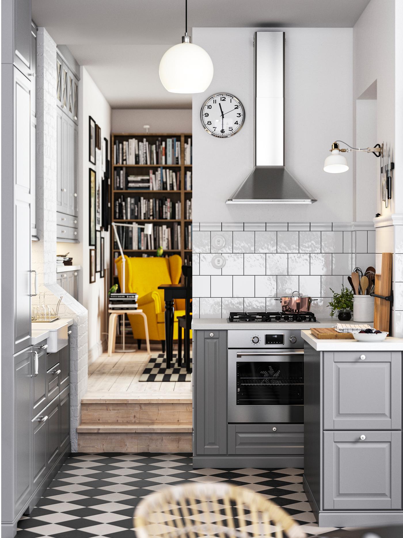 Een traditionele keuken met een geblokte vloer, grijze BODBYN keukenfronten en wit/lichtgrijze steeneffect/laminaat werkbladen.