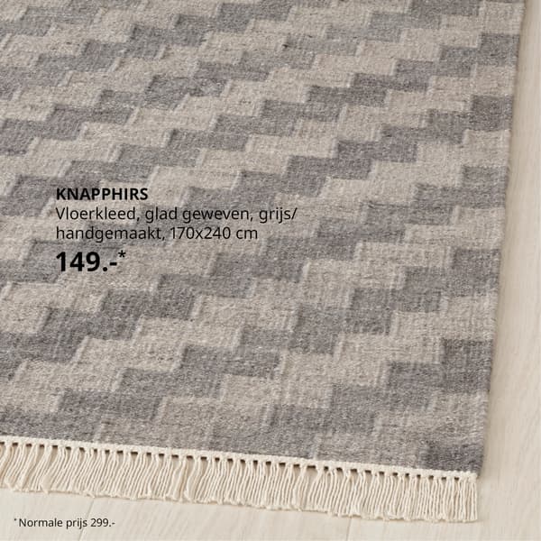 Een vloerkleed in grijs met beige franjes.