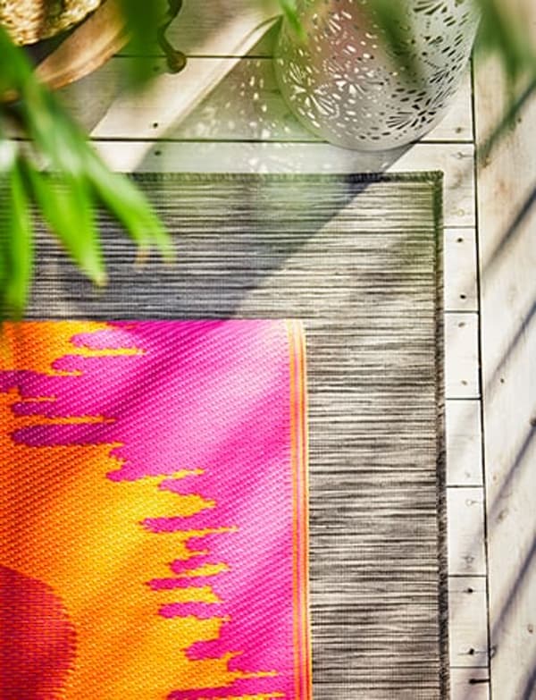 Een vloerkleed voor buiten met de kleuten oranje, rood en roze.