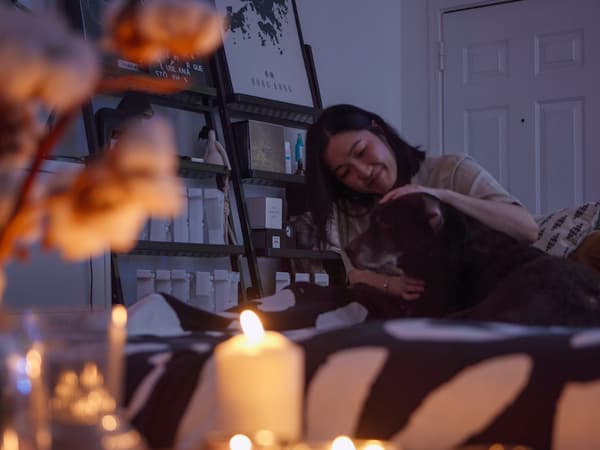 Een vrouw en een hond ontspannen zich voor een tafel vol brandende kaarsen.