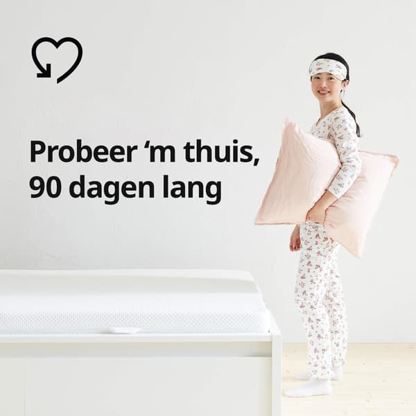 Een vrouw in haar pyjama met een kussen naast een bed en een hartje en de tekst 'Probeer 'm thuis, 90 dagen lang' op de afbeelding.