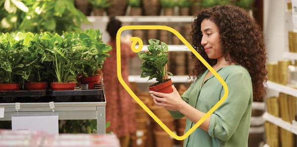 Een vrouw staat in een IKEA winkel en houdt een plantje vast.