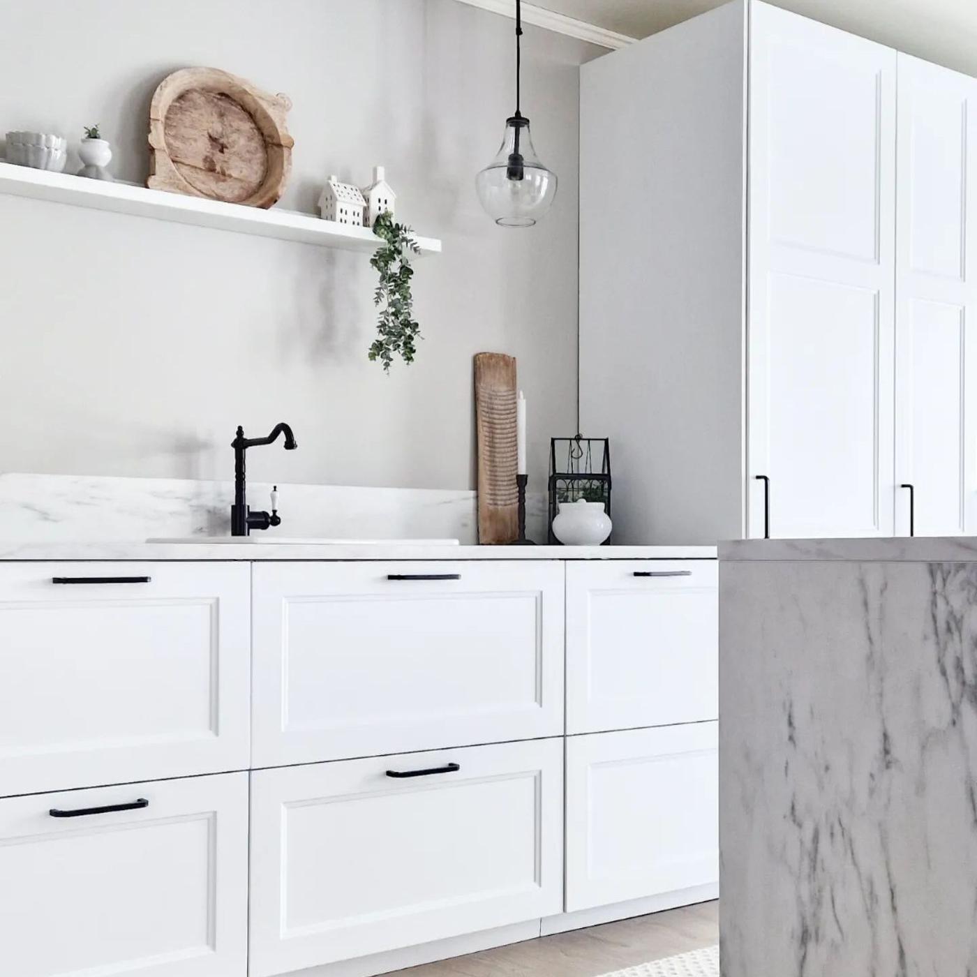 Een witte keuken met zwarte handgreepjes en een zwarte kraan