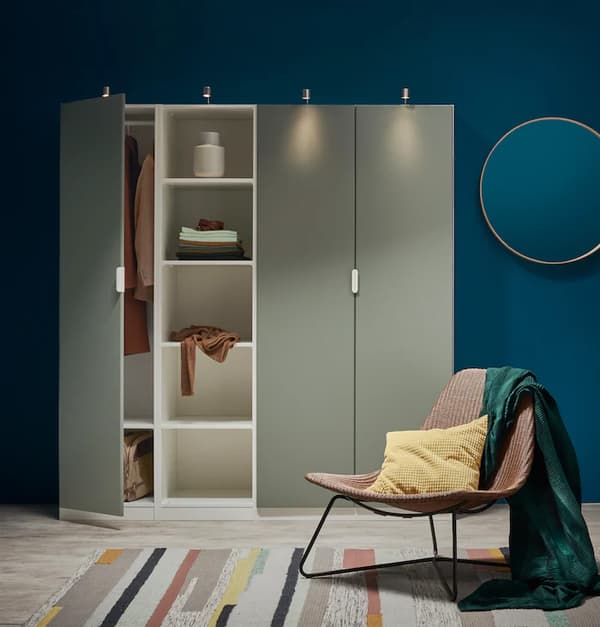 Een witte PAX kast met grijsgroene deuren en een fauteuil